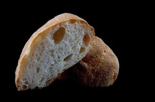 ciabatta, um pedaço de pão cortado ao meio isolado em um fundo preto. foto