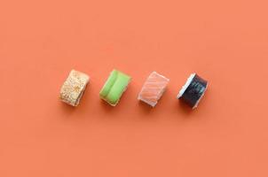 diferentes tipos de rolos de sushi asiáticos em fundo laranja. minimalismo vista superior plana lay com comida japonesa foto