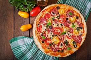 pizza com salame, tomate, queijo e azeitonas foto