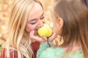 menina com mãe comendo maçã foto