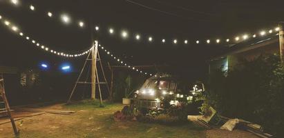 carro retrô verde decorado com parque de luz em campo verde, jardim ou gramado à noite em tom vintage. decoração e conceito de veículo antigo. foto