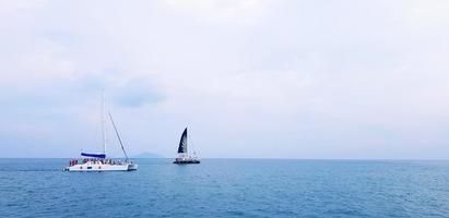 velejar e lancha no mar com céu azul e fundo de nuvens com espaço de cópia. grupo de turistas ou pessoas viajam no oceano em phuket, tailândia. faça um conceito de viagem foto