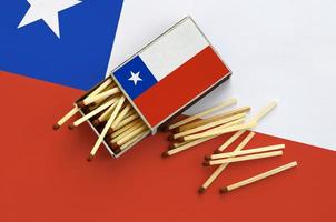 a bandeira do chile é mostrada em uma caixa de fósforos aberta, da qual vários fósforos caem e fica em uma grande bandeira foto