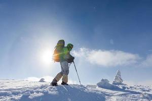 homem mochileiro caminhando nas montanhas de inverno em dia ensolarado