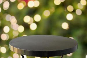 mesa redonda preta vazia com árvore de natal desfocada com fundo claro bokeh foto
