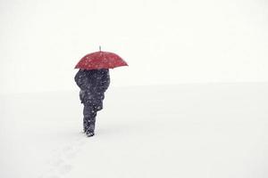 homem neve guarda-chuva vermelho colina acima foto