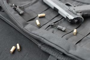 Balas e pistola de 9 mm estão em uma mochila tática preta foto