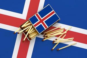 A bandeira da Islândia é mostrada em uma caixa de fósforos aberta, da qual vários fósforos caem e fica em uma grande bandeira foto
