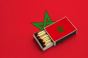 bandeira marroquina é mostrada em uma caixa de fósforos aberta, que está cheia de fósforos e fica em uma grande bandeira foto