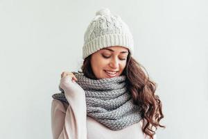 menina rindo usando chapéu de roupas quentes e cachecol isolado no fundo branco foto