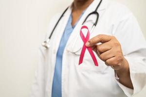 câncer de mama, mulher médica asiática com fita rosa, símbolo do dia mundial do câncer de mama. foto