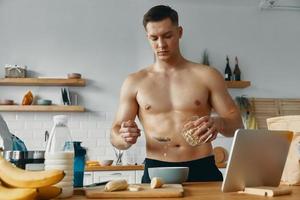 homem bonito apto preparando comida saudável em pé na cozinha foto