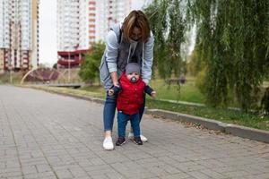 primeiros passos de um bebê pela mãe durante uma caminhada na rua foto