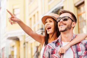 olhe lá feliz jovem casal amoroso se unindo enquanto mulher bonita apontando para longe e sorrindo foto