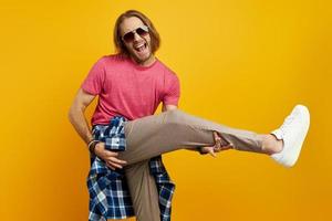 jovem brincalhão gesticulando guitarra e sorrindo em pé contra um fundo amarelo foto