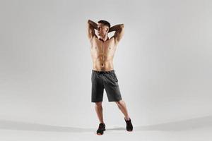 homem musculoso bonito mostrando seu corpo perfeito em pé contra um fundo branco foto