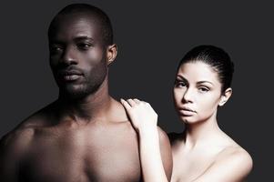 sentindo-se confiante perto dele. retrato de homem africano sem camisa e mulher caucasiana, unindo-se um ao outro em pé contra um fundo cinza foto