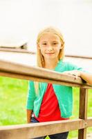 menina bonitinha. vista superior da menina bonitinha subindo por escadas de madeira ao ar livre e sorrindo foto