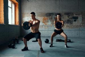 concentrado jovem e mulher fazendo musculação no ginásio foto