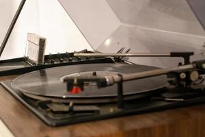 toca-discos de vinil de plataforma giratória com discos de vinil em uma mesa de madeira. disco de vinil preto foto