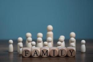 conceito de família feliz, grupo de boneca de madeira vivendo junto com amor e bloco de madeira com letras de família de palavras. foto