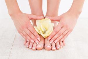 linda manicure e pedicure. close-up de jovem tocando seus pés em pé no chão de madeira foto