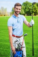 meu motorista favorito feliz jovem golfista mostrando motorista e motorista em pé no verde foto