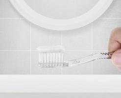 homem limpando os dentes no banheiro, ele está tomando sua escova de dentes foto