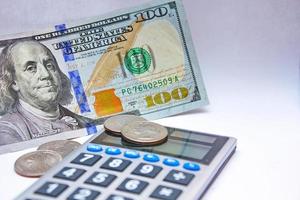 calculadora e notas de dólar são colocadas em uma mesa branca. foto