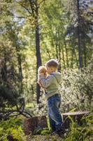 um menino bonito está brincando com um filhote de urso na floresta. os raios do sol envolvem o espaço da clareira com um toco. uma história mágica de interações para o livro. espaço para copiar. seletivo foto