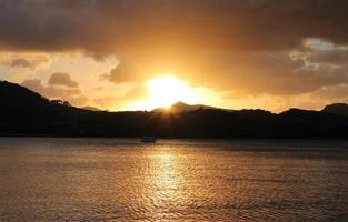 incrível pôr do sol dourado sobre colinas e oceano foto