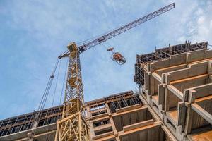 um tiro de ângulo baixo de um guindaste com equipamento em um canteiro de obras com uma nova infraestrutura de construção. despejando concreto em um molde foto