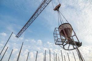 um tiro de ângulo baixo de um guindaste com equipamento em um canteiro de obras perto de uma nova infraestrutura de construção foto