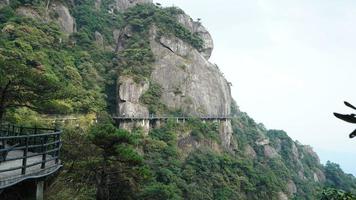 as belas paisagens das montanhas com a floresta verde e uma estrada de prancha construída ao longo da face de um penhasco na zona rural da china foto