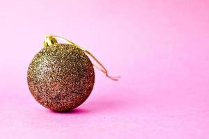 amarelo dourado pequeno vidro redondo plástico inverno inteligente brilhante decorativo linda bola de natal festiva de natal, brinquedo de natal colado com lantejoulas em um fundo rosa violeta foto