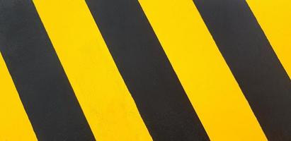parede pintada de preto e amarelo para plano de fundo ou papel de parede. linha de tráfego no piso ou no solo. foto