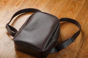 mochila de couro ou bolsa de couro marrom em um fundo de madeira. foto