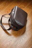 mochila feita de couro genuíno marrom em um fundo de madeira. foto
