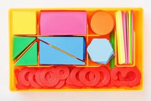 uma caixa com figuras de plástico coloridas e números em um fundo branco. jogos educativos para crianças. foto