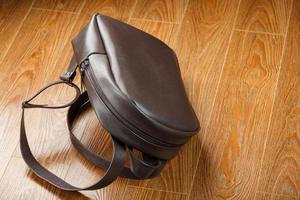 mochila feita de couro genuíno marrom em um fundo de madeira. foto