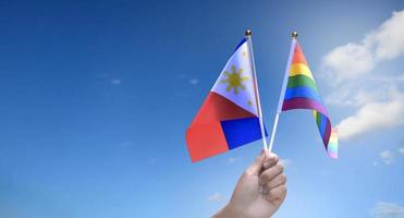 bandeira do arco-íris e bandeira nacional das filipinas segurando na mão, foco suave e seletivo, conceito para celebração do lgbtq no mês do orgulho em todo o mundo. foto