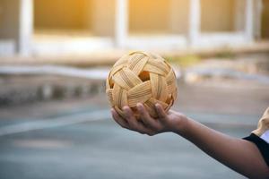 bola sepak takraw, esporte tradicional dos países do sudeste asiático, segurando na mão do jovem jogador sepak takraw feminino asiático na frente da rede antes de jogá-lo para outro jogador para chutar a rede. foto