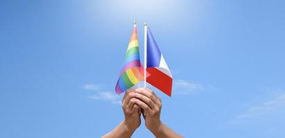 bandeira do arco-íris e bandeira nacional francesa segurando nas mãos, foco suave e seletivo, conceito para celebração dos gêneros lgbtq no mês do orgulho em todo o mundo. foto