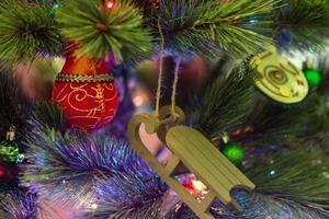 decorações de natal coloridas em uma árvore de abeto com luzes borradas. foto