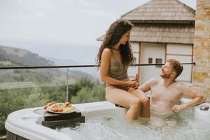 jovem casal desfrutando na banheira de hidromassagem ao ar livre de férias foto