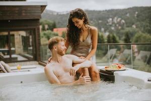 jovem casal desfrutando na banheira de hidromassagem ao ar livre de férias foto