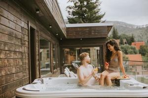jovem casal desfrutando na banheira de hidromassagem ao ar livre de férias foto