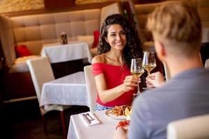 jovem casal almoçando com vinho branco no restaurante foto