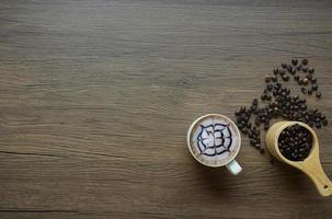 café em uma caneca com tela de grão de madeira e grãos de café em uma colher foto