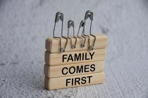alfinete de segurança modelo da família sentada em blocos de madeira com texto - a família vem em primeiro lugar. conceito de família foto